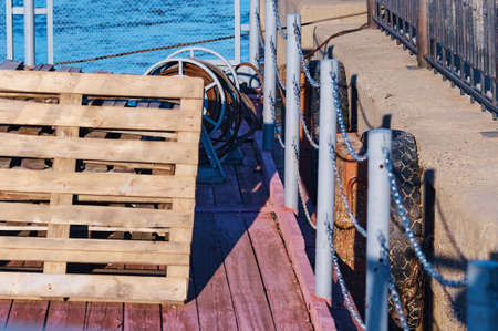 Old car tires used on the pier. To make the boat dock soft, prevent bumps. Wooden deck, metal railing and rope reel. The concept of reuse. selective focus.の写真素材