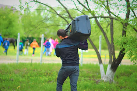 The guy carries a huge boombox on his shoulder. back view. Spring party outdoors in the style of the...