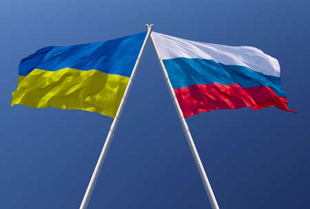 Flags of Russia and Ukraine against a blue sky. Escalation of the conflict. The concept of confrontation. Abstract collage.の写真素材