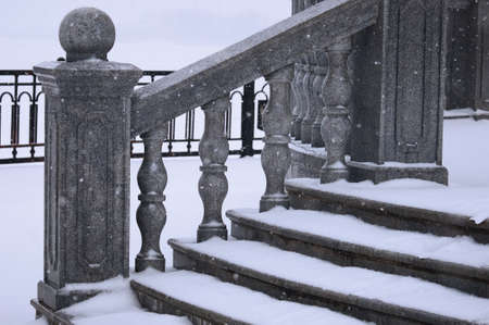 A close view of the granite steps under the snow. Balustrade stairs on the embankment on a winter morning during a snowfall. selective focus.の写真素材