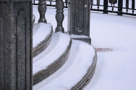 A close view of the granite steps under the snow. Balustrade stairs on the embankment on a winter morning during a snowfall. selective focus.の写真素材