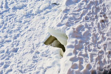 Deep crack on the snow-covered ice of the Amur River on a sunny day. footprints. Fracture of the ice...