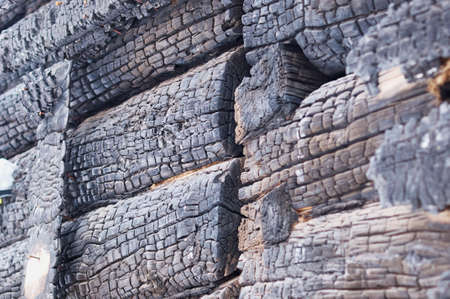 Fragment of a burn log hut. After the fire. Texture of charred wood. selective focus.の写真素材