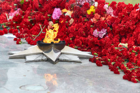 Festive background of Victory Day. Eternal flame against the background of carnations, a monument - a symbol of May 9, the memory of the war. selective focus. copyspace.の写真素材