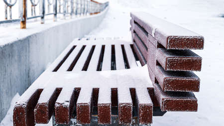 Brown standing lonely bench in the snow white and fluffy. Winter day.