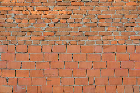 Vintage red brick wall. The whole and broken. The bricks are lit by the rising sun.