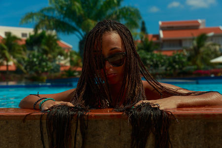 Beautiful slim girl having fun near the warm blue water with palm trees on background.の写真素材