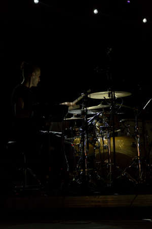 Audience with hands raised at a music festival and lights streaming down from above the stage. Soft focus, high ISO, grainy image.のeditorial素材