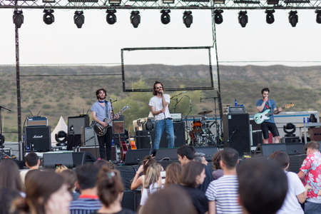 Audience with hands raised at a music festival and lights streaming down from above the stage. Soft focus, high ISO, grainy image.のeditorial素材