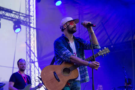 Audience with hands raised at a music festival and lights streaming down from above the stage. Soft focus, high ISO, grainy image.のeditorial素材