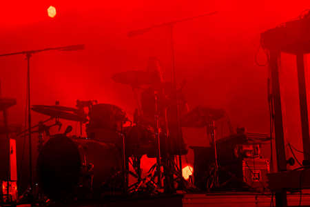 Audience with hands raised at a music festival and lights streaming down from above the stage. Soft focus, high ISO, grainy image.のeditorial素材