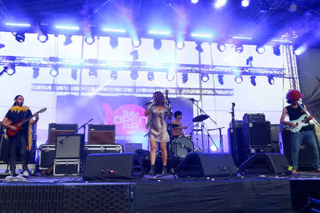 Audience with hands raised at a music festival and lights streaming down from above the stage. Soft focus, high ISO, grainy image.のeditorial素材