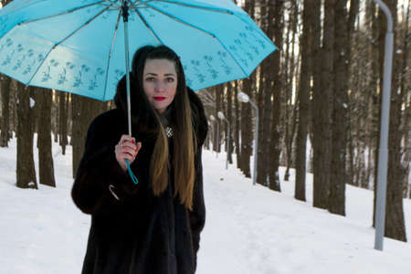 beautiful girl with umbrella in the Park in the winterの写真素材