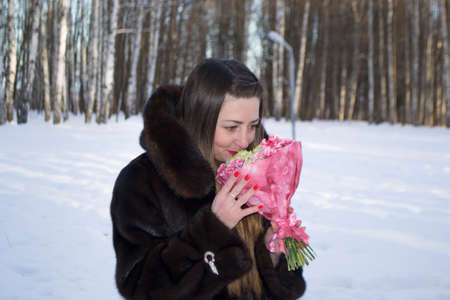 beautiful girl with bouquet of flowers in the winterの写真素材