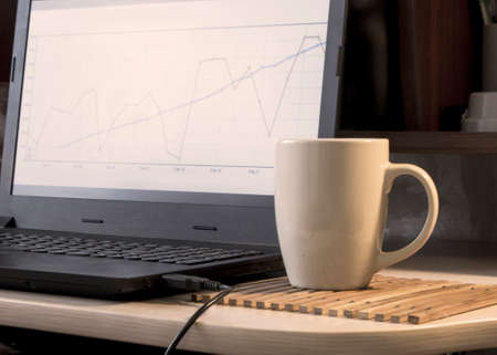 the man at the computer watching charts and drinking coffee