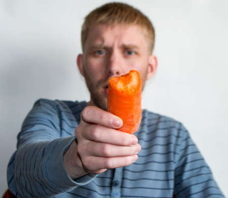 guy eats carrots on a white backgroundの写真素材