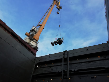 Feeding the tractor into the hold. Port work. Dockers working day. Portal crane in action. Hard and...