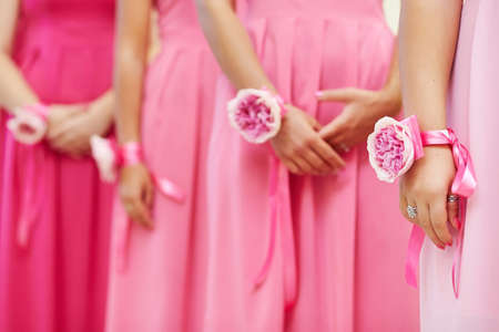 Hands of bridesmaids with peony flowers bracelet in pink dressesの写真素材