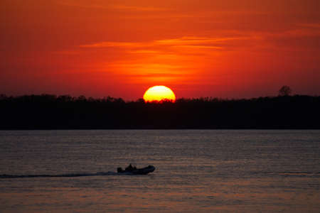 Big Sun and Fisherman in an inflatable boat. High quality photoの写真素材