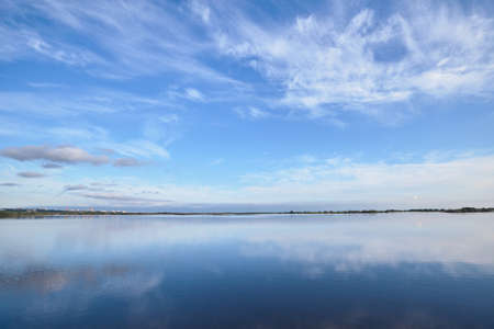 Smooth water surface under blue sky