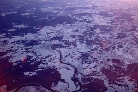 Twilight view on snowy ground from airplane in winter