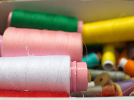 Old multi-colored coils lie in a box. A pile of coils with colored threads. Sewing supplies. Many coils of thread. Old multi-colored coilsの写真素材