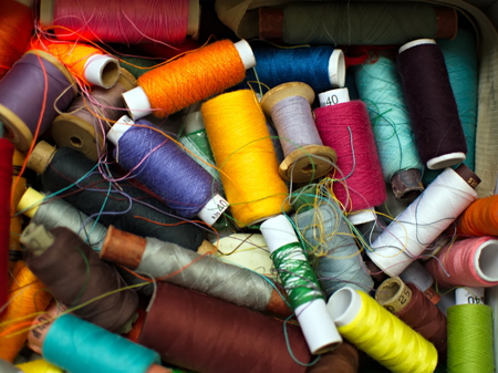 Old multi-colored coils lie in a box. A pile of coils with colored threads. Sewing supplies. Many coils of thread. Old multi-colored coilsの写真素材