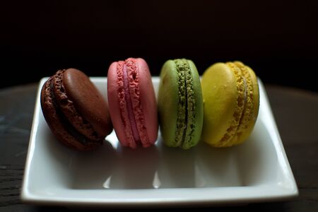 Multi-colored macaroons on a wooden tray. Pink, yellow and green macaroon.