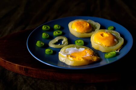 Fried eggs on blue plate. Fried eggs in a plate on a black table. Scrambled eggsの写真素材