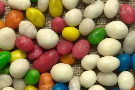 Multicolored round candy lying on the burlap. Multi-colored candies dragee. Small round candyの写真素材