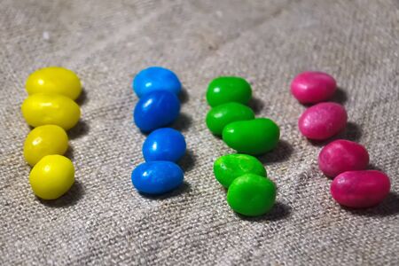Multicolored round candy lying on the burlap. Multi-colored candies dragee. Small round candyの写真素材