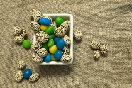 Multicolored round candy lying on the burlap. Multi-colored candies dragee. Small round candyの写真素材