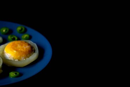 Fried eggs on blue plate. Fried eggs in a plate on a black table. Scrambled eggsの写真素材