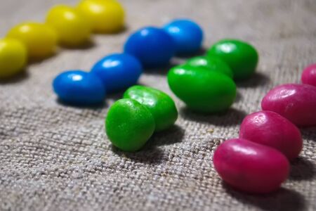 Multicolored round candy lying on the burlap. Multi-colored candies dragee. Small round candyの写真素材