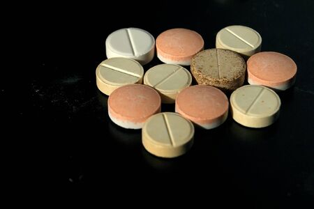 Multi-colored pills on a black table. Multi-colored round pills.の写真素材