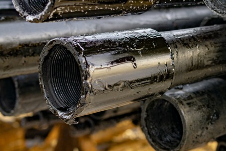 Oil Drill pipe. Rusty drill pipes were drilled in the well section. Downhole drilling rig. Laying the pipe on the deck. View of the shell of drill pipes laid in courtyard of the oil and gas warehouse.の写真素材