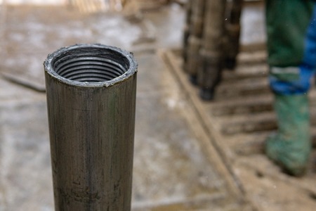 Offshore oil rig worker prepare tool and equipment for perforation oil and gas well at wellhead platform. Making up a drill pipe connection. A view for drill pipe connection from between the stands.の写真素材