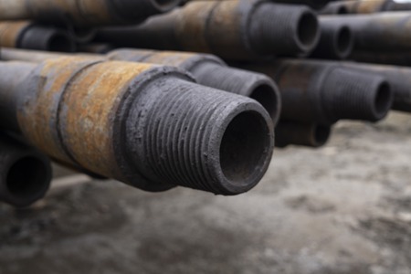 Drilling pipe. Rusty drill pipes were drilled in the well section. Downhole drilling rig. Laying the pipe on the deck. View of the shell of drill pipes and pipes laid in the open courtyard of the oil and gas warehouse.の写真素材