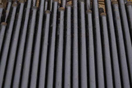 Oil Drill pipe. Rusty drill pipes were drilled in the well section. Downhole drilling rig. Laying the pipe on the deck. View of the shell of drill pipes laid in courtyard of the oil and gas warehouse.の写真素材