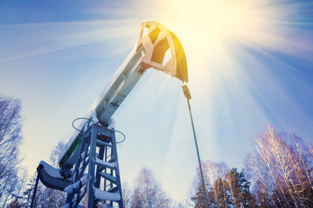 Oil field with pump jack, profiled on blue sky with white clouds, on a sunny day in springの写真素材