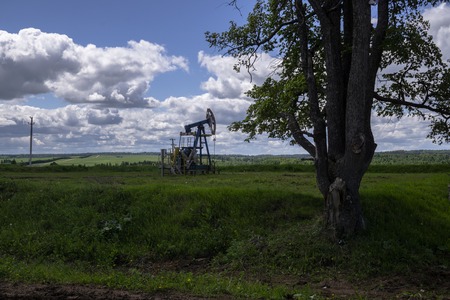 The beam pumping unit is homework, sunset in oil field. Oil pump oil rig energy industrial machine for petroleum. The pumping unit as the pump installed on a well. Equipment of oil fieldsの写真素材