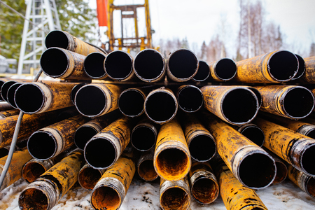 Salvaged pipes and casings are lined up on racks in storage on a California oil lease. Drill pipes with oil drops.の写真素材