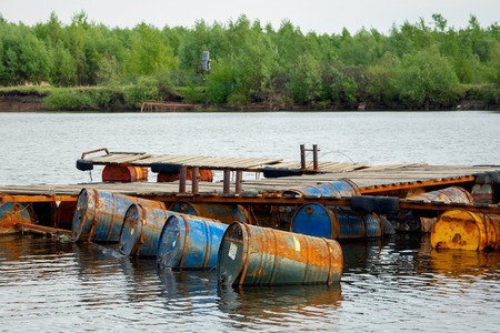 dumped oil drums cause pollution in the water, more and more the water is polluted by throwing away waste which therefore gets into the rivers. Polluted river full of various garbageの写真素材