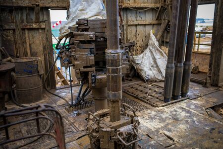 Offshore oil rig worker prepare tool and equipment for perforation oil and gas well at wellhead platform. Making up a drill pipe connection. A view for drill pipe connection from between the standsの写真素材