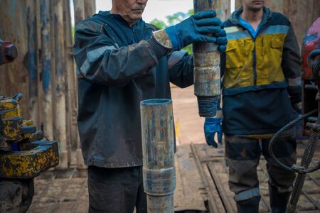 Offshore oil rig worker prepare tool and equipment for perforation oil and gas well at wellhead platform. Making up a drill pipe connection. A view for drill pipe connection from between the standsの写真素材