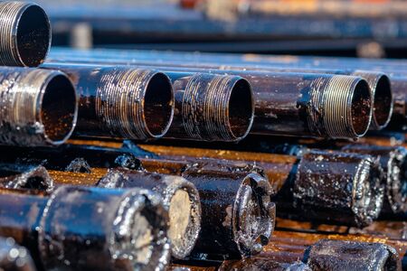 Oil Drill pipe. Rusty drill pipes were drilled in the well section. Downhole drilling rig. Laying the pipe on the deck. View of the shell of drill pipes laid in courtyard of the oil and gas warehouseの写真素材