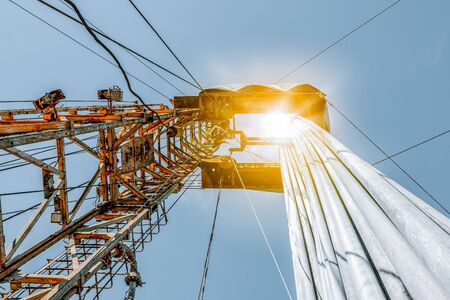 Onshore land rig in oil and gas industry. Oil drilling rig against a blue sky with clouds.
