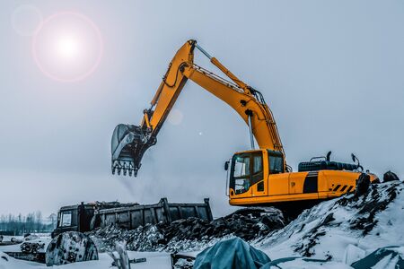 Excavator is loading excavation to the truck. Excavators are heavy construction equipment consisting of a boom, dipper or stick , bucket and cab on a rotating platform