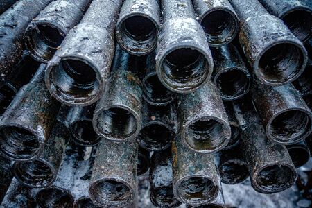Oil Drill pipe. Rusty drill pipes were drilled in the well section. Downhole drilling rig. Laying the pipe on the deck. View of the shell of drill pipes laid in courtyard of the oil and gas warehouse.の写真素材