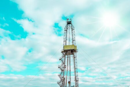 Onshore land rig in oil and gas industry. Oil drilling rig against a blue sky with cloudsの写真素材
